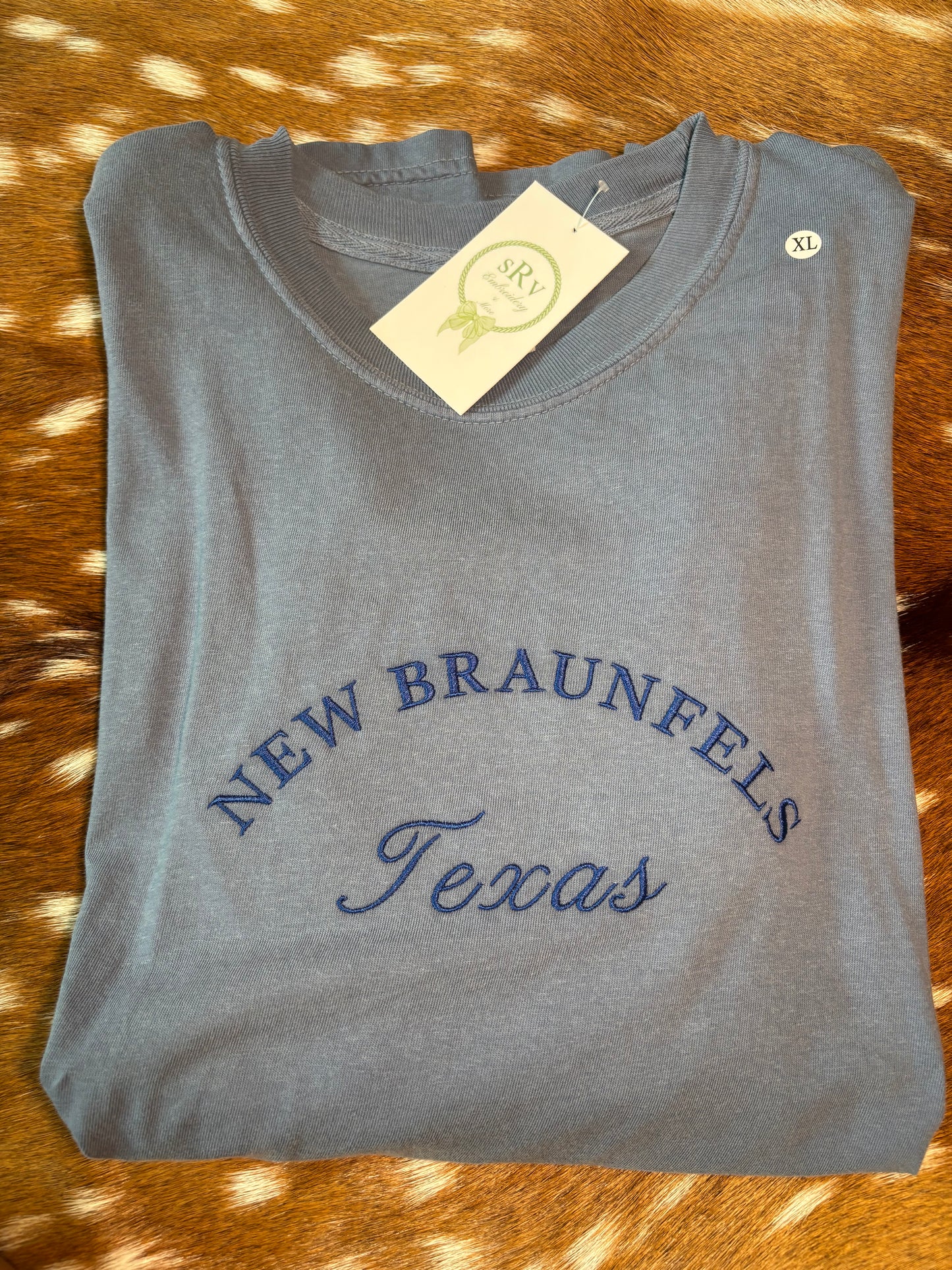 Comfort colors denim blue tshirt with “New Braunfels Texas” in royal blue thread unisex